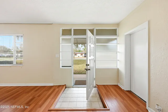 a view of an empty room with wooden floor and a window