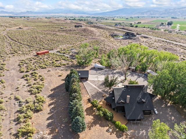 460 Omni Point Road Central Valley, UT 84754 - Photo 92 of 101 Expansive property featuring a multi-level residence with a dark shingle roof, surrounding mature trees, a detached accessory structure, a paved driveway, and natural, arid landscaping
