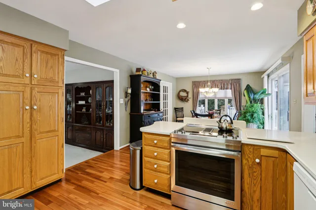 a view of a kitchen with a stove wooden floor windows and a livingroom