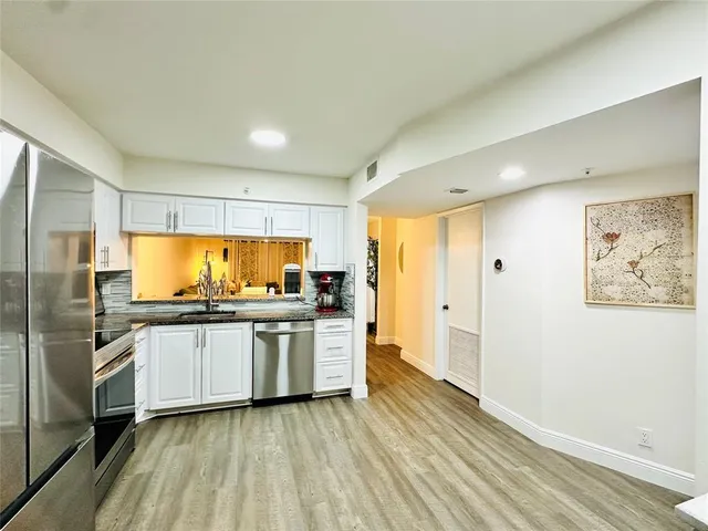 a kitchen with stainless steel appliances granite countertop a refrigerator and a stove top oven