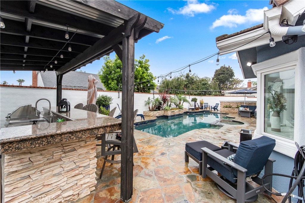 Luxurious backyard retreat featuring a custom pool, spa, and expansive covered outdoor kitchen.