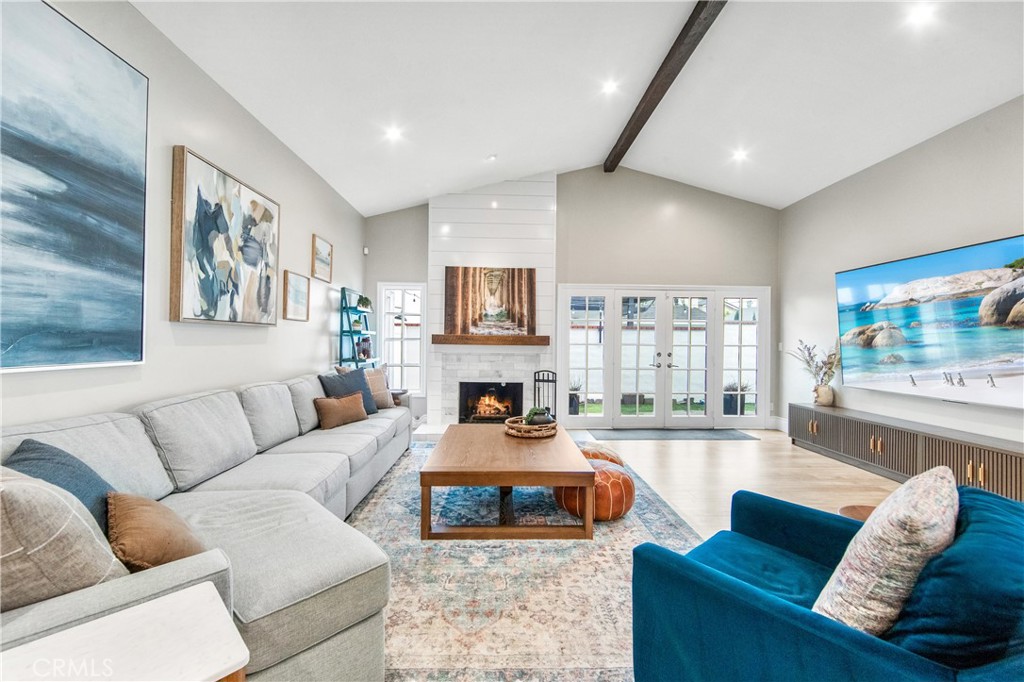 5522 Mossvale Circle Huntington Beach, CA 92649 - Photo 2 of 61 Expansive light-filled living room with vaulted ceilings, exposed beam, marble fireplace, and wall-to-wall French doors.