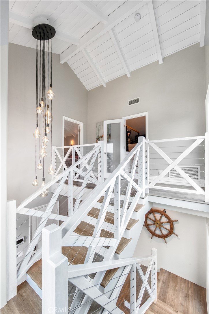 5522 Mossvale Circle Huntington Beach, CA 92649 - Photo 23 of 61 Sun-drenched custom staircase with nautical-inspired railings winds to a mezzanine retreat, complete with a cozy reading nook framed by two-story windows.