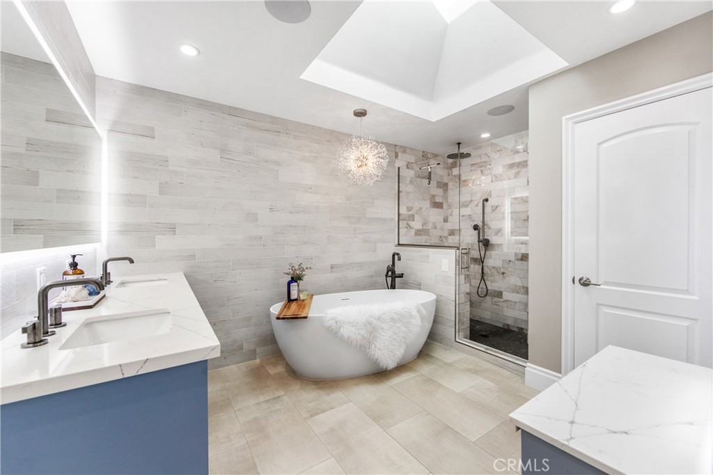 5522 Mossvale Circle Huntington Beach, CA 92649 - Photo 29 of 61 Luxurious spa bath featuring a sculptural soaking tub, marble shower, illuminated vanities, designer lighting, and custom closet.