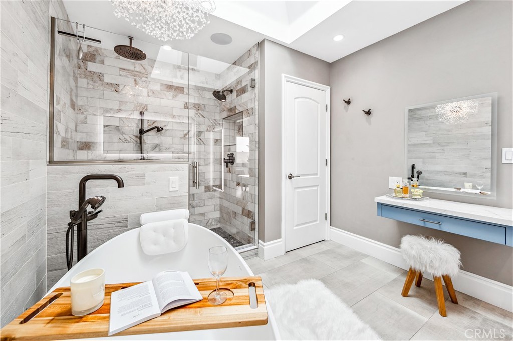 5522 Mossvale Circle Huntington Beach, CA 92649 - Photo 30 of 61 Luxurious spa bath featuring a sculptural soaking tub, marble shower, illuminated vanities, designer lighting, and custom closet.
