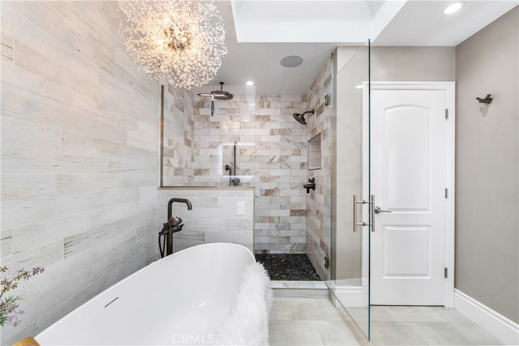 5522 Mossvale Circle Huntington Beach, CA 92649 - Photo 31 of 61 Luxurious spa bath featuring a sculptural soaking tub, marble shower, illuminated vanities, designer lighting, and custom closet.