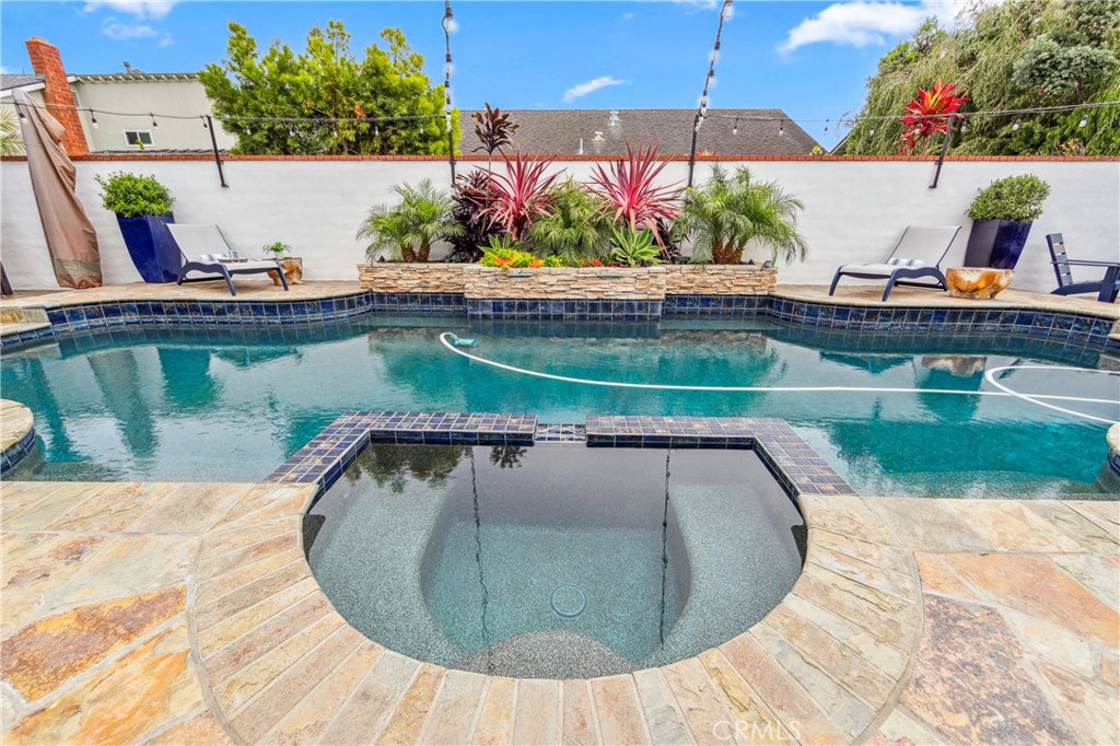 5522 Mossvale Circle Huntington Beach, CA 92649 - Photo 51 of 61 Custom curved pool with central spa, navy tile, stacked stone waterfall, and elegant entry steps.