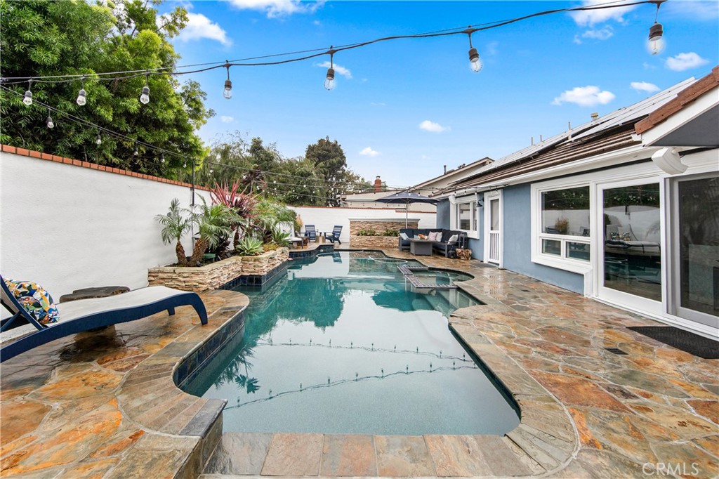 5522 Mossvale Circle Huntington Beach, CA 92649 - Photo 53 of 61 Custom curved pool with central spa, navy tile, stacked stone waterfall, and elegant entry steps.