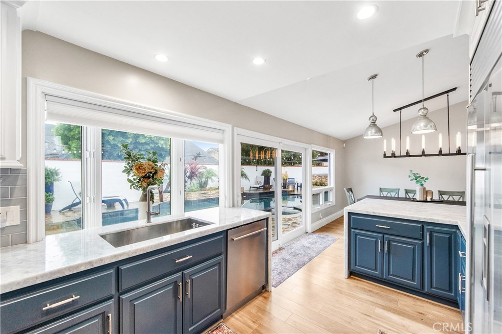 5522 Mossvale Circle Huntington Beach, CA 92649 - Photo 10 of 61 Luxury kitchen featuring waterfall marble, custom navy cabinetry, farmhouse sink, high-end appliances, and backyard views.