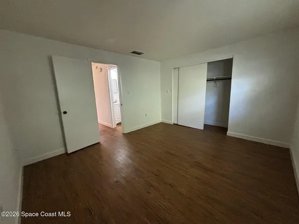 an empty room with wooden floor and closet