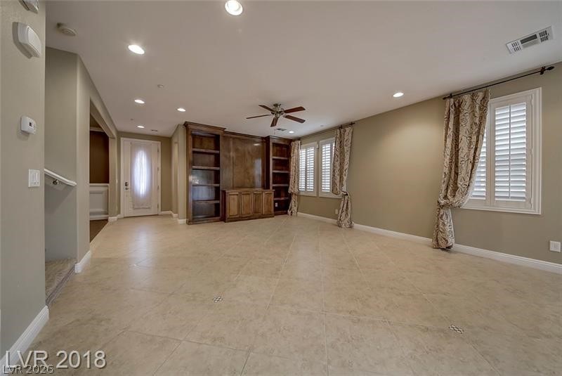 3144 Whitfeild Avenue Henderson, NV 89044 - Photo 14 of 55 A spacious living room features built-in shelving, elegant window shutters, and tiled flooring.