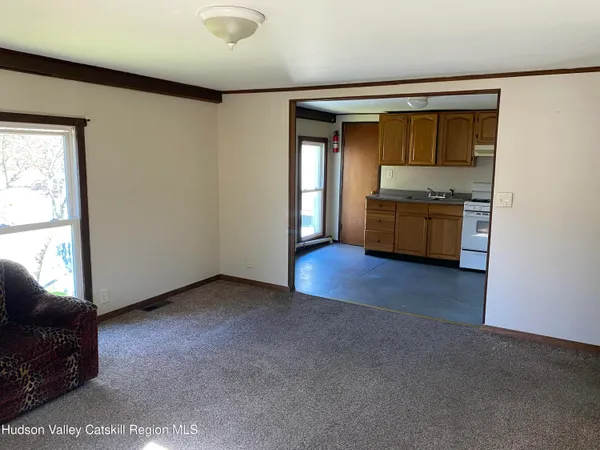 a view of an empty room with a window and kitchen view