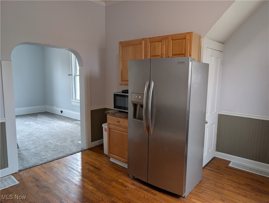 10143 Pleasant Road Pleasant City, OH 43772 - Photo 9 of 32 Kitchen with stainless steel refrigerator with ice dispenser, arched walkways, dark wood-type flooring, and wainscoting
