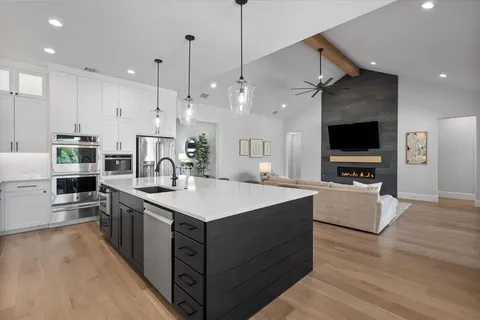 a large kitchen with stainless steel appliances a large counter top a stove a sink and a refrigerator