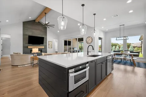 a large kitchen with stainless steel appliances a large center island attached withe living room