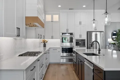 a kitchen with stainless steel appliances a sink a stove a refrigerator and a center island