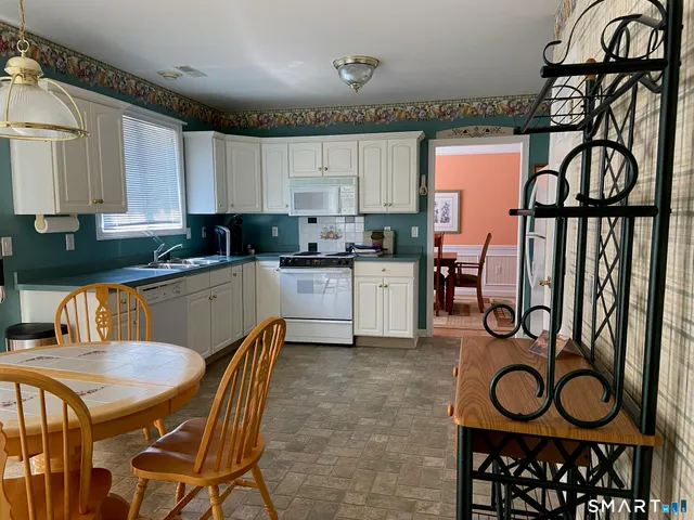 a kitchen with kitchen island granite countertop a stove top oven a sink a dining table and chairs