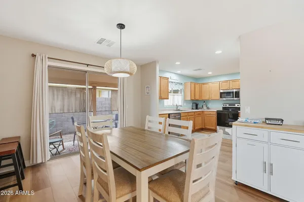 a kitchen with stainless steel appliances kitchen island granite countertop a stove a sink a dining table and chairs with wooden floor