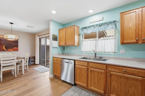 a kitchen with stainless steel appliances granite countertop a sink dishwasher a refrigerator and cabinets with wooden floor