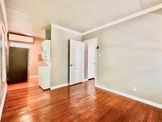 a view of an empty room with wooden floor and a bathroom