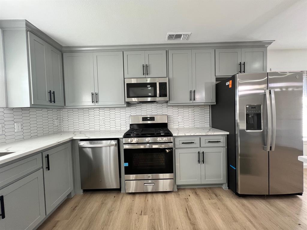 a kitchen with cabinets stainless steel appliances and wooden floor