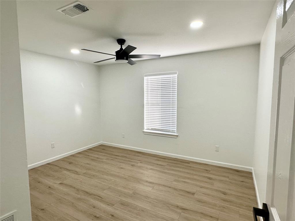 601 Short Street McKinney, TX 75069 - Photo 21 of 28 an empty room with wooden floor ceiling fan and windows
