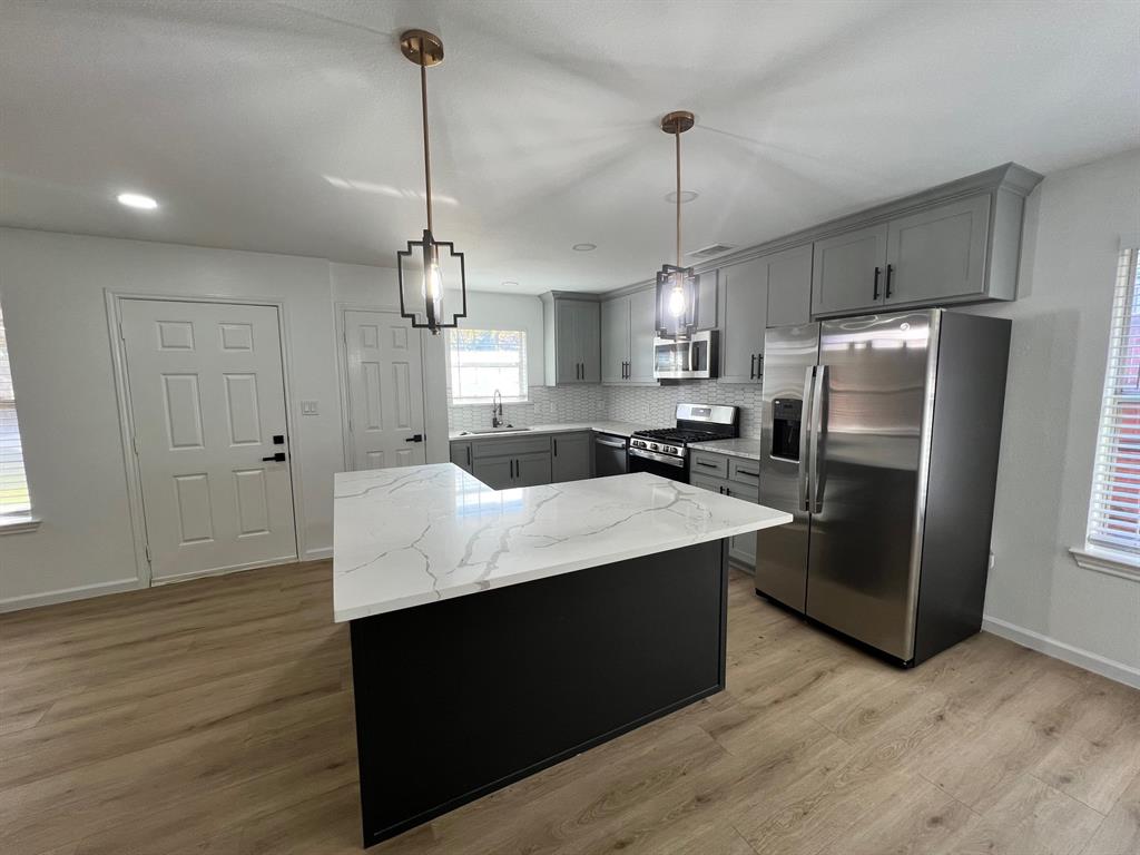 601 Short Street McKinney, TX 75069 - Photo 22 of 28 a kitchen with kitchen island a counter top space wooden floor and a refrigerator