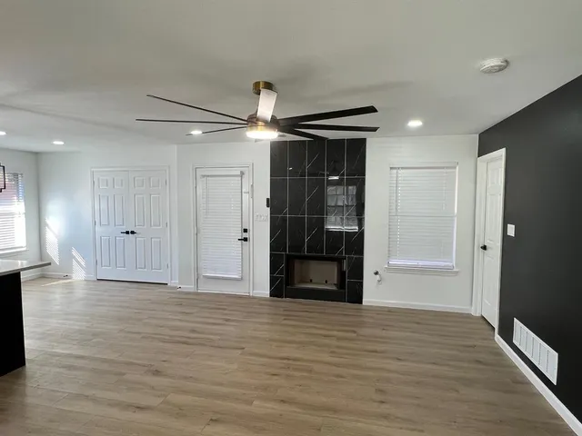 a view of empty room with wooden floor and refrigerator