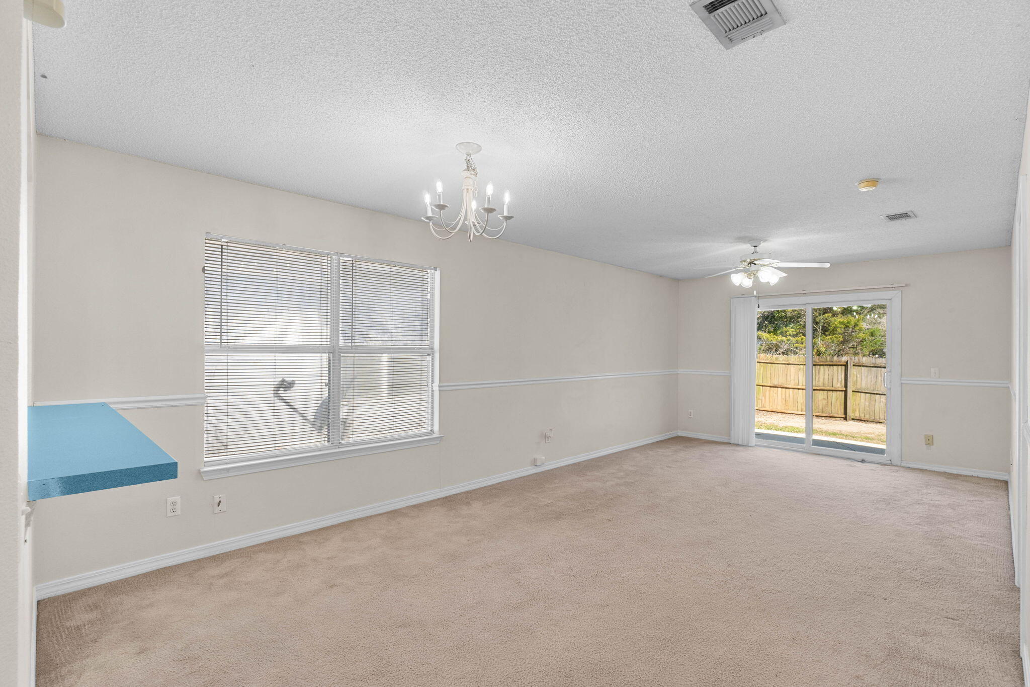 7612 Chablis Circle Navarre, FL 32566 - Photo 6 of 28 an empty room with windows and chandelier fan