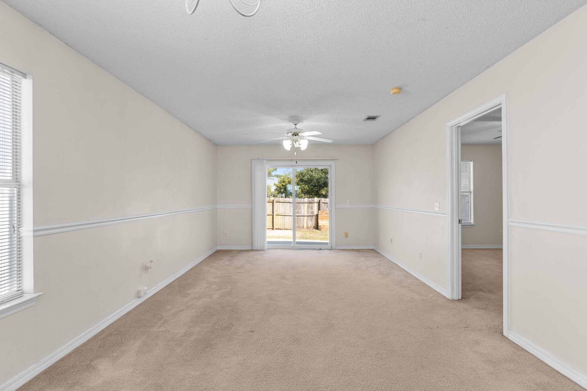 7612 Chablis Circle Navarre, FL 32566 - Photo 7 of 28 an empty room with windows and chandelier