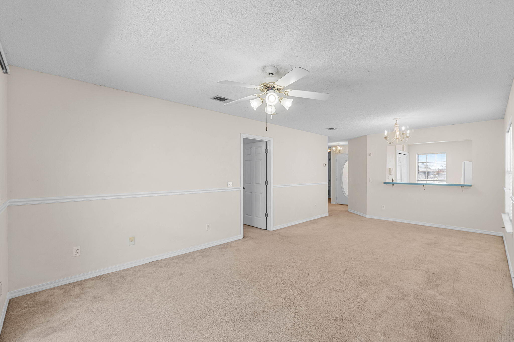 7612 Chablis Circle Navarre, FL 32566 - Photo 8 of 28 an empty room with chandelier fan and windows