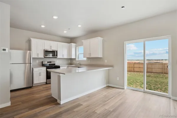 a view of kitchen with stainless steel appliances granite countertop a stove top oven a sink and a white cabinets