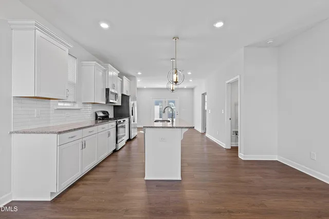 a large kitchen with stainless steel appliances granite countertop a sink a stove cabinets and wooden floor