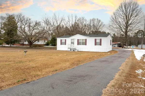 a front view of a house with a big yard and large trees