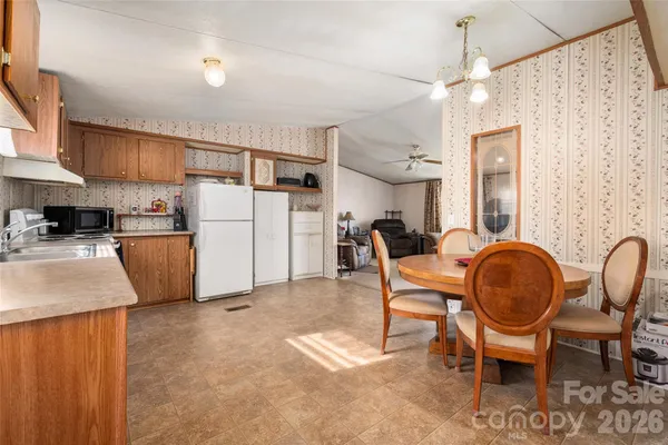 a kitchen with refrigerator a dining table and chairs