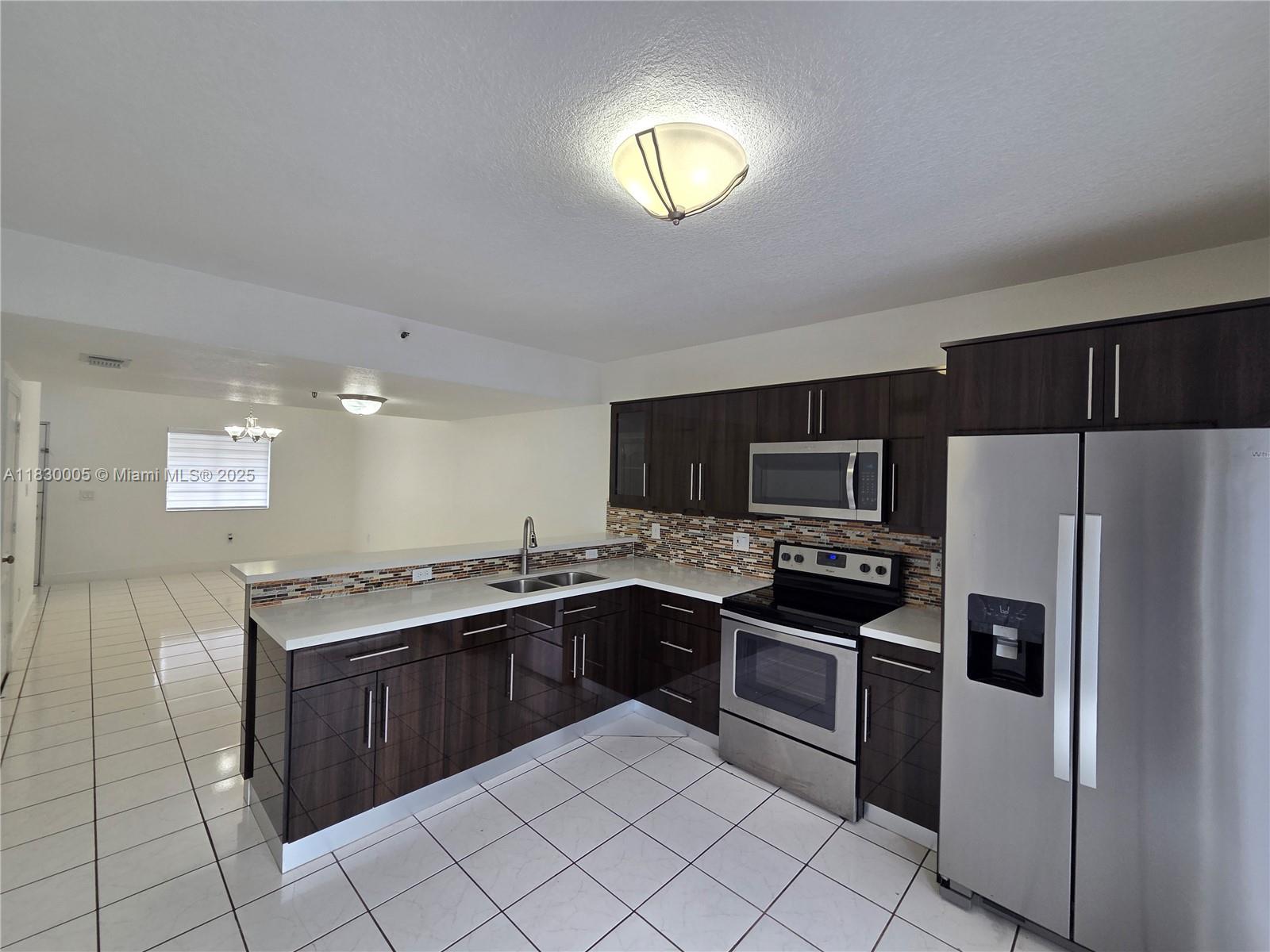 8360 Northwest 103rd Street, Unit 207E Hialeah Gardens, FL 33016 - Photo 3 of 25 a kitchen with stainless steel appliances granite countertop a stove microwave and sink