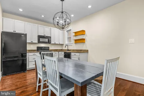 a kitchen with stainless steel appliances granite countertop a dining table chairs and a refrigerator