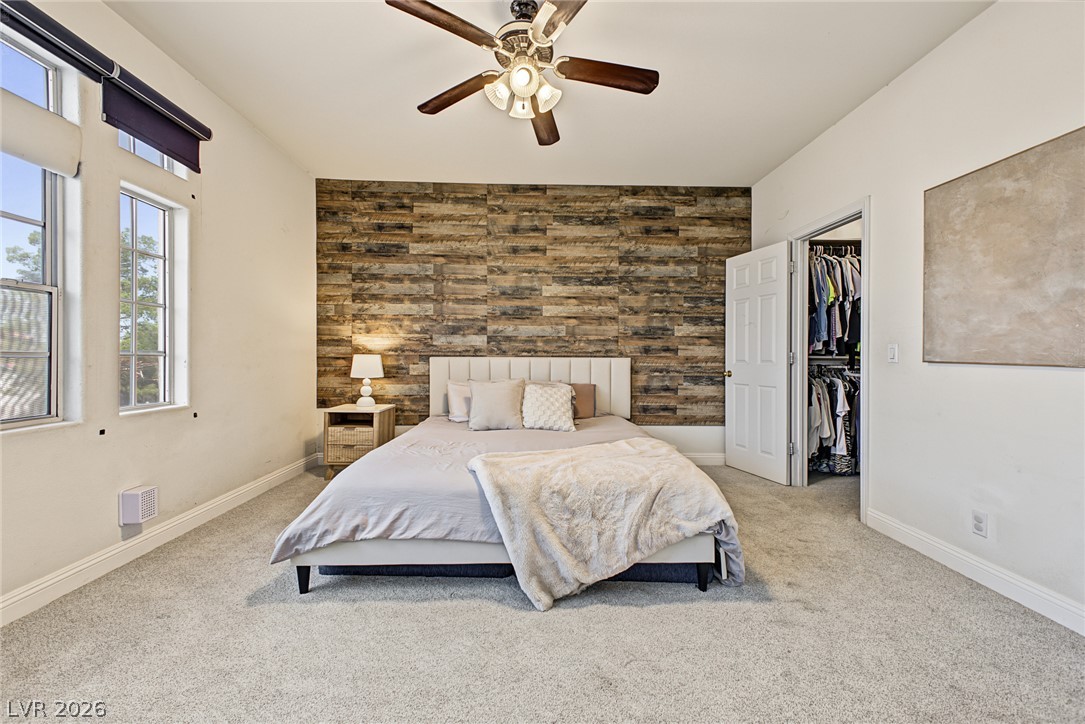 A rustic wood-plank accent wall anchors this comfortable bedroom featuring soft carpeting.
