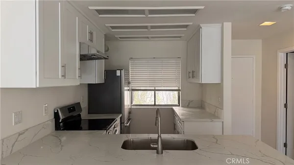 a kitchen with white cabinets and window