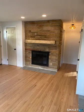 an empty room with wooden floor fireplace and windows