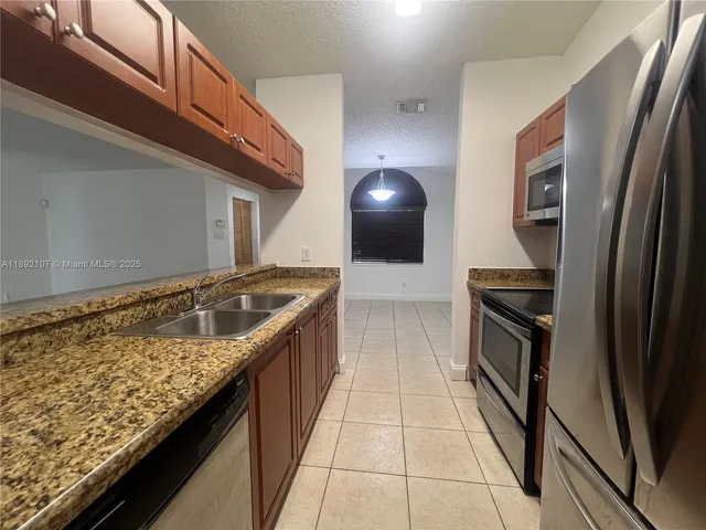 a kitchen with stainless steel appliances granite countertop a sink and a refrigerator