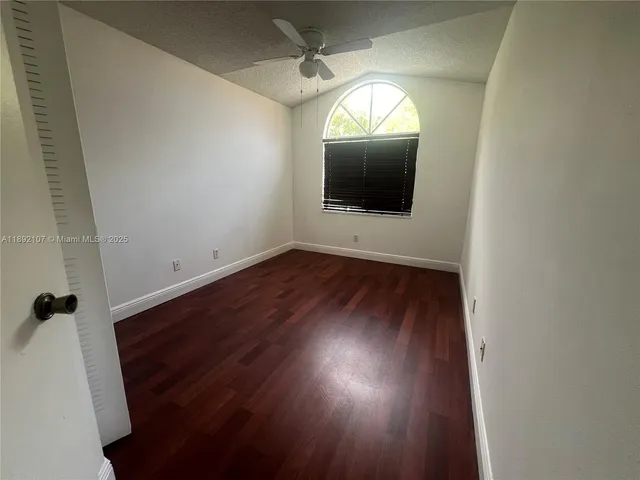 an empty room with wooden floor and a chandelier fan