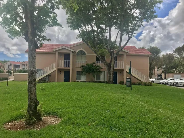 a view of a house with a big yard plants and large trees