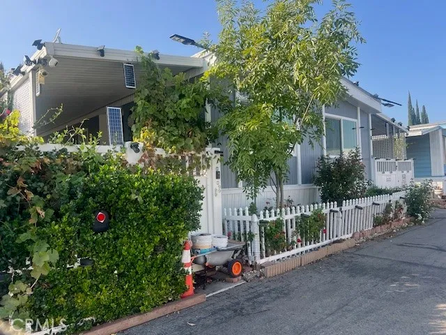 a view of a house with wooden fence and trees in the background