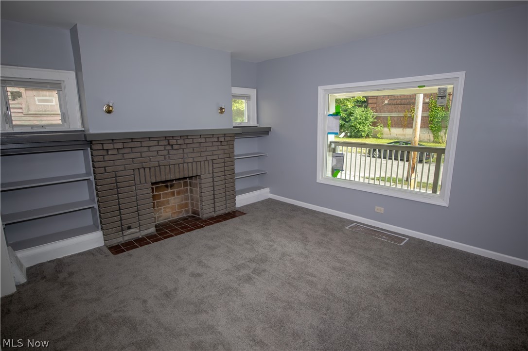 9505 Aetna Road Cleveland, OH 44105 - Photo 9 of 25 Unfurnished living room featuring dark carpet and a brick fireplace