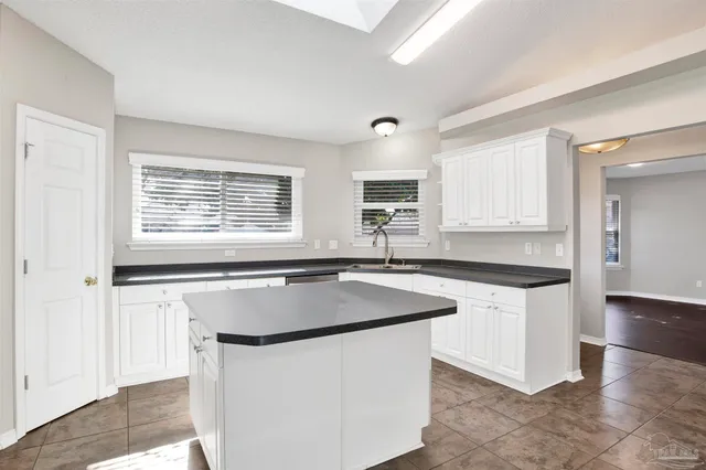 a kitchen with granite countertop a sink a counter space and cabinets