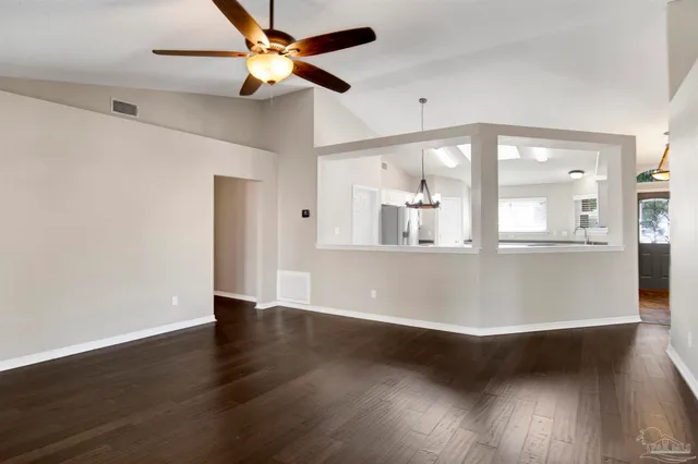 a view of an empty room with wooden floor and a fan