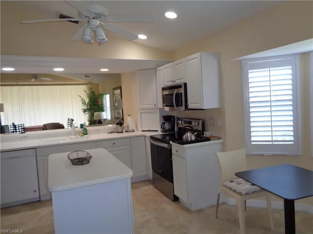 a kitchen with a sink a stove a refrigerator cabinets and a dining table