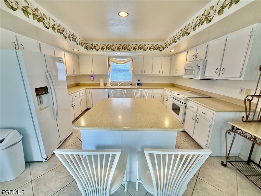 1400 Graham Circle Lehigh Acres, FL 33936 - Photo 22 of 47 a kitchen with stainless steel appliances granite countertop a sink a stove a refrigerator with white cabinets and wooden floor