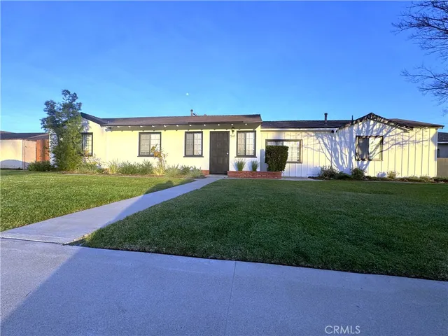a view of a house next to a big yard and large trees
